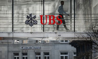 A employee is seen in silhouette with sign of Swiss giant banking UBS and a sign of Credit Suisse bank in Zurich on March 20.