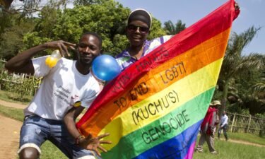 Ugandan men hold a rainbow flag reading "Join hands to end LGBTI (Lesbian Gay Bi Trans Intersex - called Kuchu in Uganda) genocide" as they celebrate on August 9