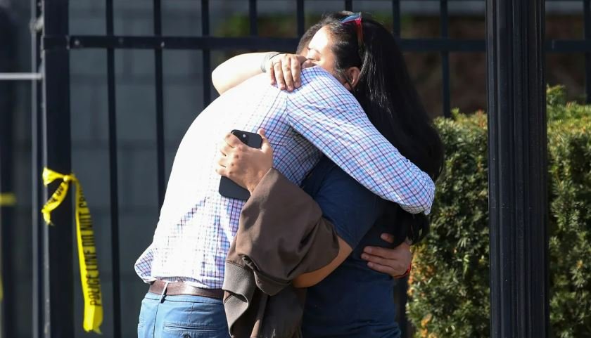 <i>Michael Clevenger/Courier Journal/AP</i><br/>Two people embrace outside the building where a mass shooting happened in Louisville on Monday.