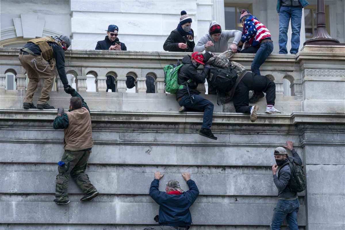 FILE - Rioters loyal to President Donald Trump climb the west wall of the the U.S. Capitol, Jan. 6, 2021, in Washington. 