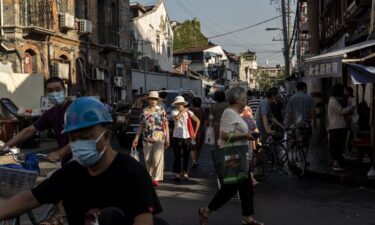 Residents walk past street stalls in an older neighborhood in Shanghai