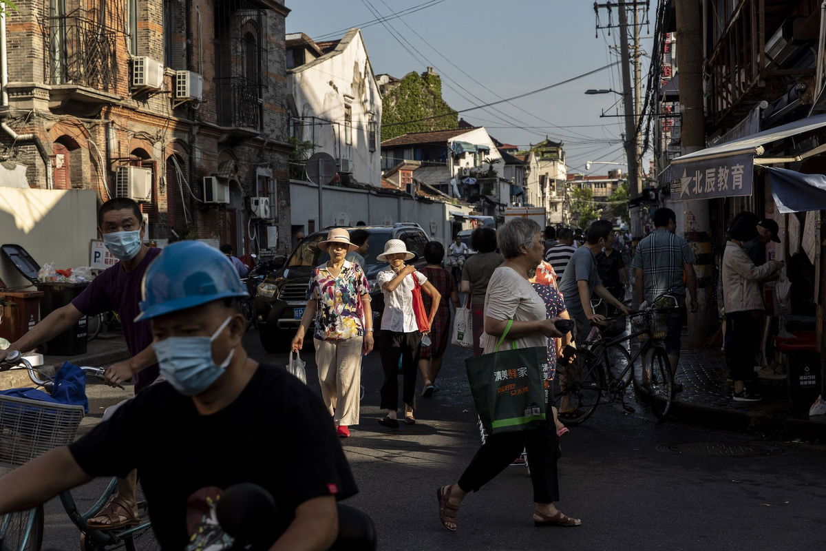 <i>Qilai Shen/Bloomberg/Getty Images/FILE</i><br/>Residents walk past street stalls in an older neighborhood in Shanghai