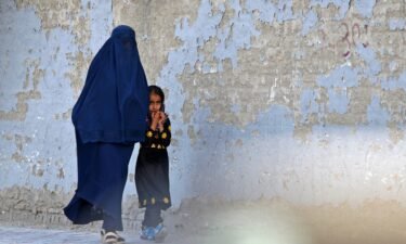 A burqa-clad woman walks with a girl along a street in Kabul on May 7
