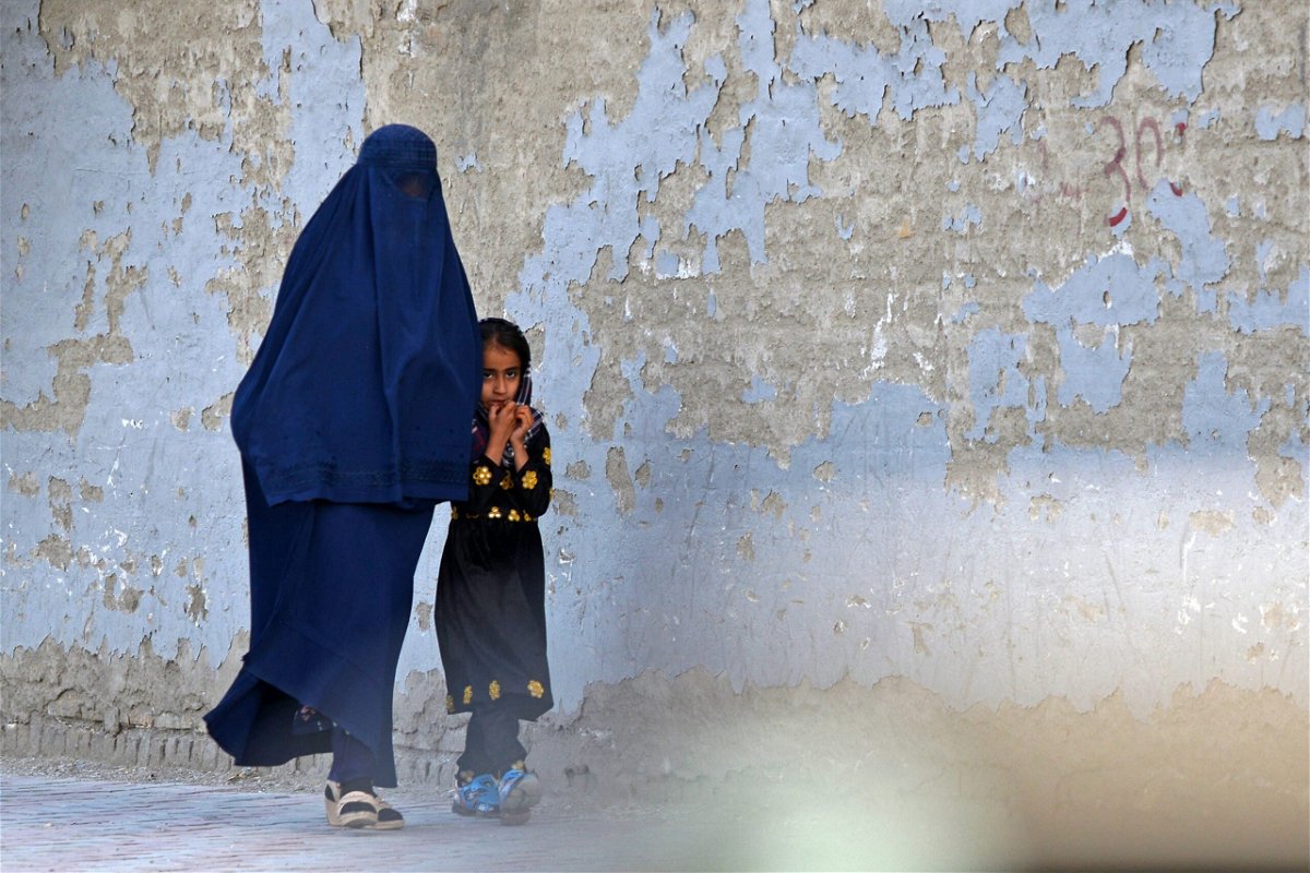 <i>Ahmad Sahel Arman/AFP via Getty Images</i><br/>A burqa-clad woman walks with a girl along a street in Kabul on May 7