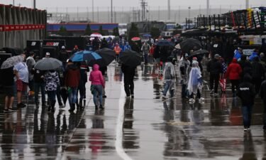 Race fans walk through the garage area while rain causes a delay to a NASCAR Cup Series race at Charlotte Motor Speedway on Sunday.