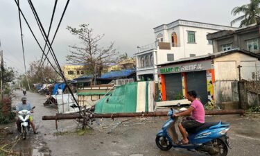 Residents ride motorcycles past broken utility poles in Sittwe