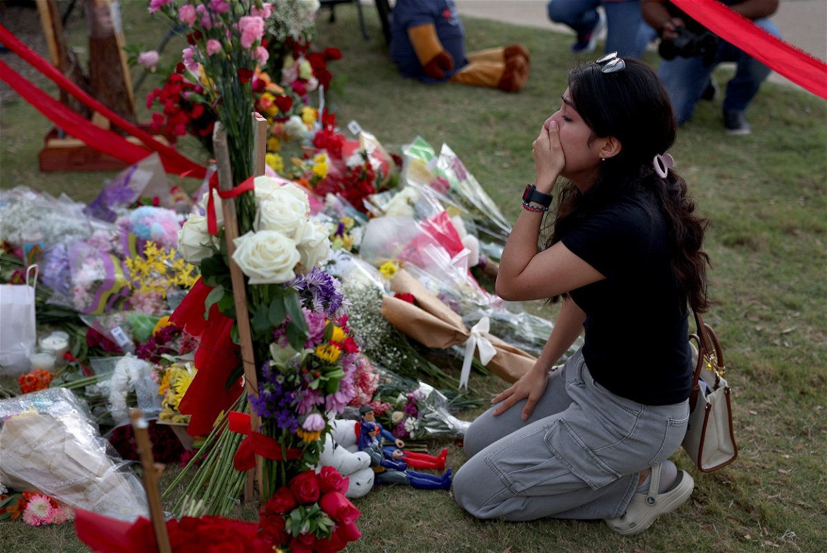 <i>Joe Raedle/Getty Images</i><br/>A mourner grieves on May 8th at a makeshift memorial at Allen Premium Outlets.