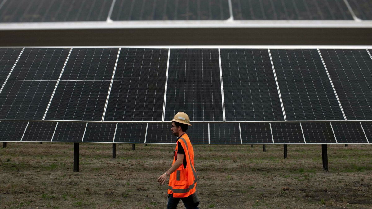 <i>Mark Felix/AFP/Getty Images</i><br/>An ENGIE employee walks past solar panels at the ENGIE Sun Valley Solar project in Hill County