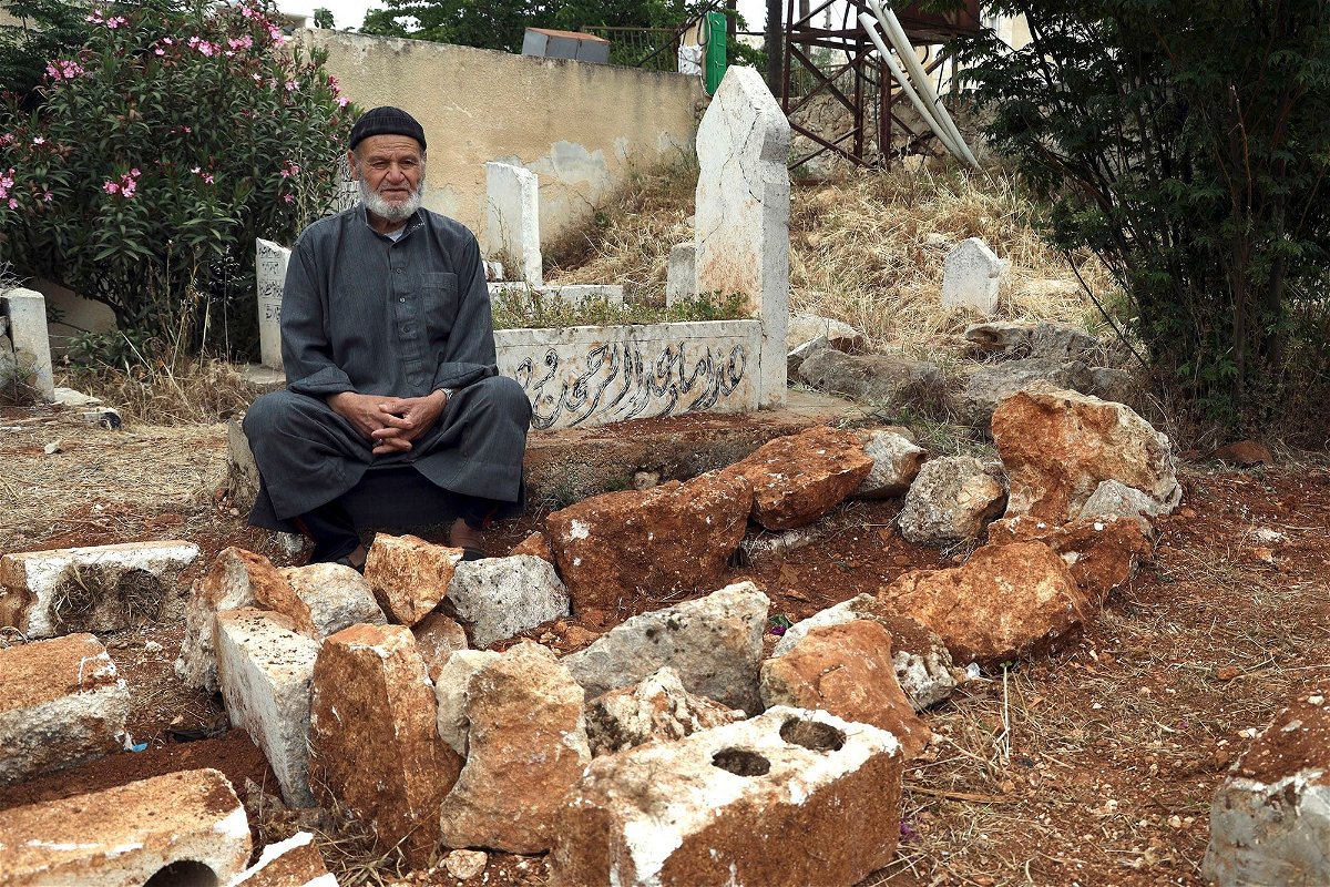 <i>Omar Albam/AP</i><br/>Mohammad Mesto sits next to the grave of his brother Lutfi