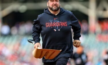 A member of the Cleveland Guardians grounds crew leaves the field after collecting a bird that was struck and killed on the infield.