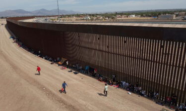 Migrants camp out next to the border barrier between El Paso