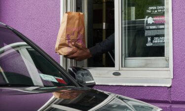 A worker hands food to a drive-through customer at a Taco Bell restaurant in Elmont