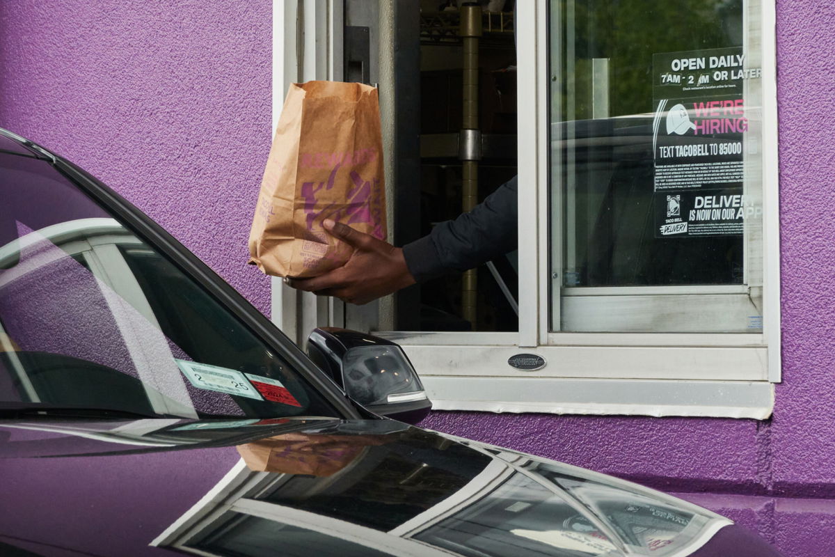 <i>Bing Guan/Bloomberg/Getty Images</i><br/>A worker hands food to a drive-through customer at a Taco Bell restaurant in Elmont
