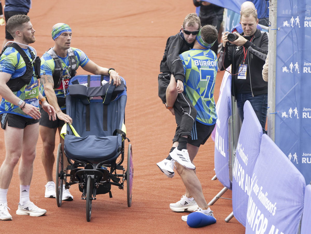 <i>Danny Lawson/PA/AP</i><br/>Sinfield carries Burrow across the finish line of the Rob Burrow Leeds Marathon at Headingley Stadium.