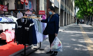 A customer browses through discount clothing displayed outside a shop in Beijing on May 10.