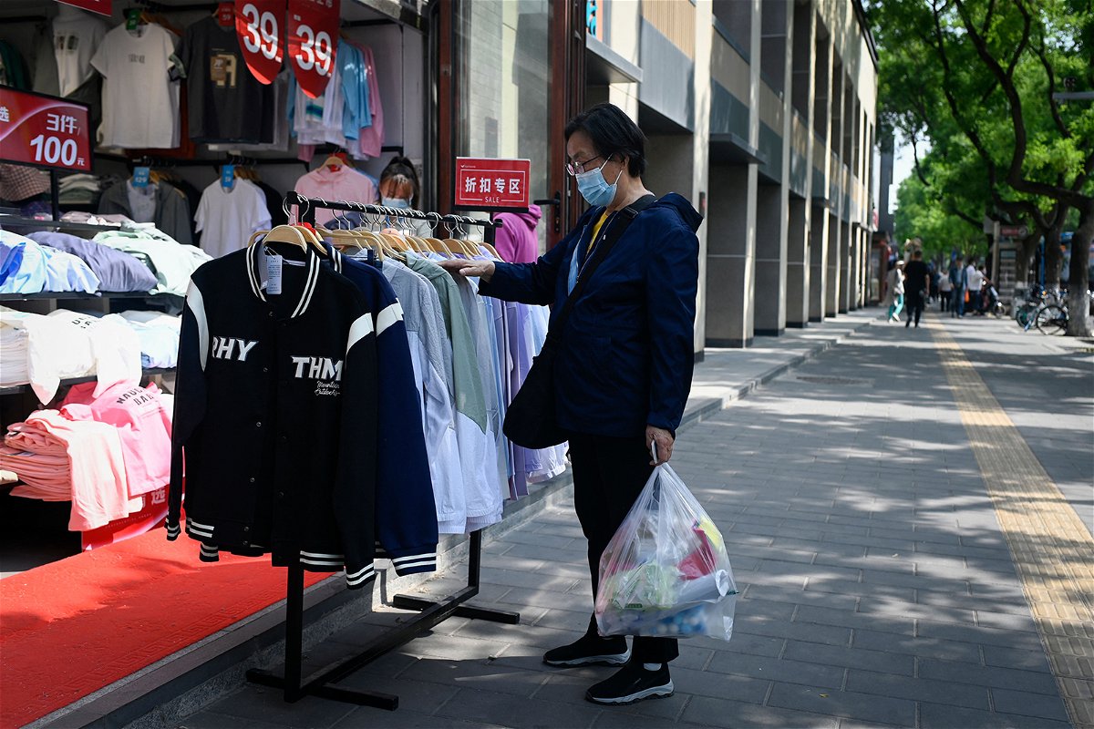 <i>Wang Zhao/AFP/Getty Images</i><br/>A customer browses through discount clothing displayed outside a shop in Beijing on May 10.