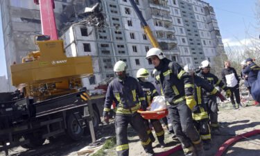 Rescuers carry the body of a victim found under the rubble at a block of flats destroyed in a Russian rocket attack on Uman