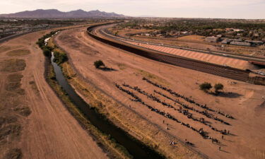 Migrants stand near the border wall after crossing the Rio Bravo river with the intention of turning themselves in to the U.S. Border Patrol agents