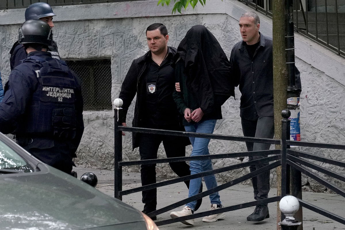 <i>Oliver Bunic/AFP/Getty Images</i><br/>Police officers escort a minor