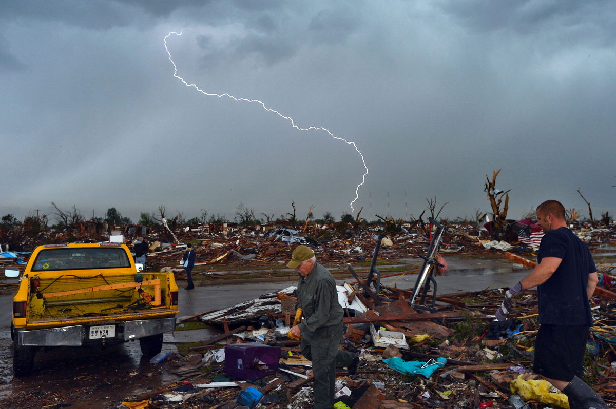 <i>Jewel Samad/AFP/Getty Images</i><br/>Lightning strikes as tornado survivors search for items at their devastated home on May 23