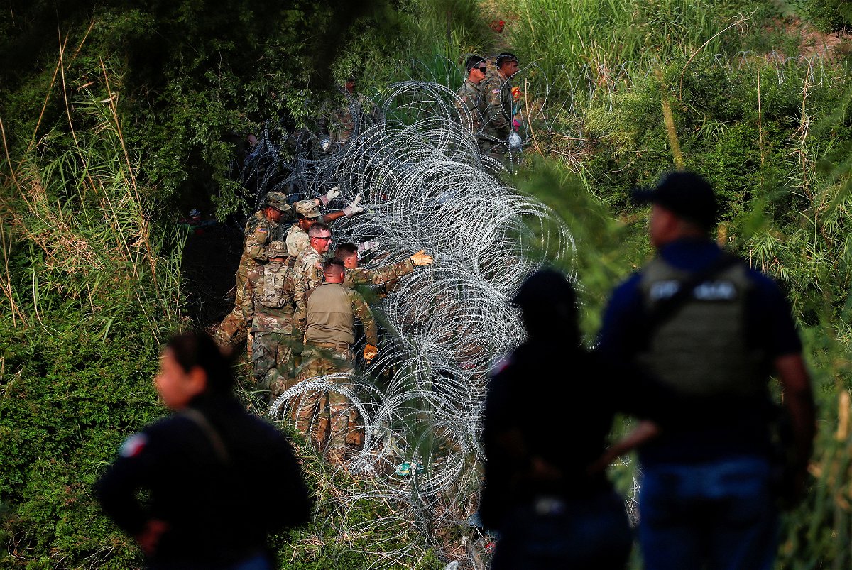 <i>Daniel Becerril/c</i><br/>Texas National Guard soldiers place more razor wire on the banks of the Rio Bravo river in Matamoros