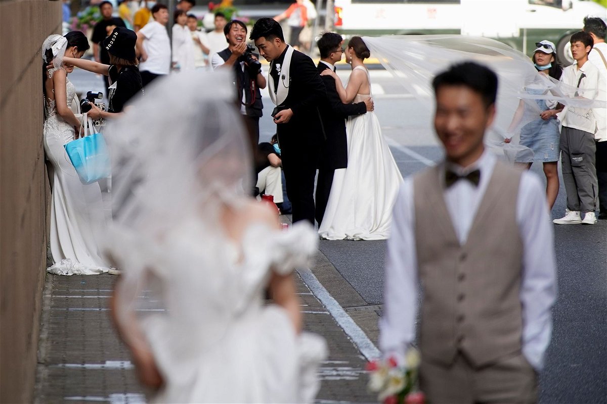 <i>Aly Song/Reuters/File</i><br/>Couples prepare to get their photo taken during a wedding photography shoot on a street in Shanghai in 2021.