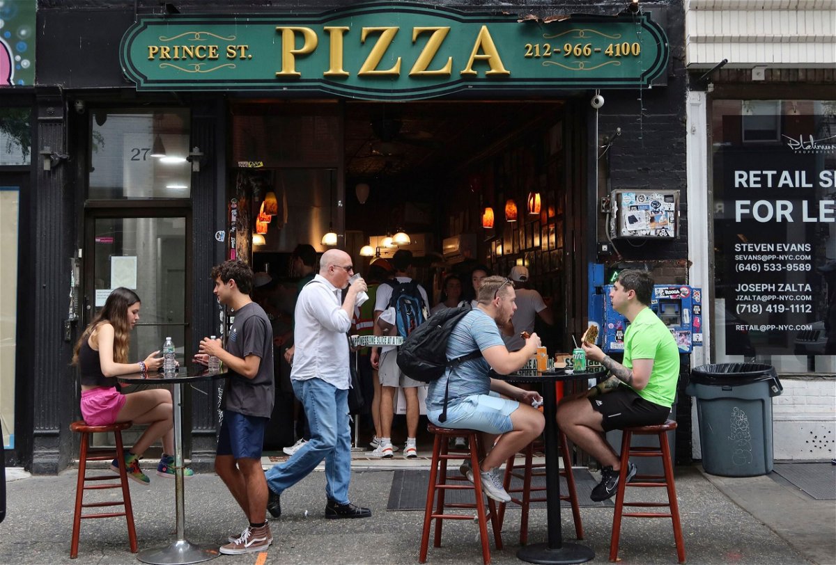 <i>Gary Hershorn/Corbis News/Getty Images</i><br/>People eat at tables on the sidewalk outside Prince St. Pizza on June 25 in New York City.