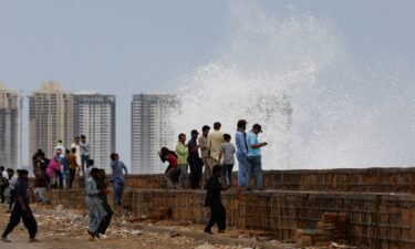 People gather near the rising waves