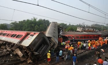 Rescue workers gather around damaged carriages during search for survivors at the accident site of a three-train collision near Balasore in the eastern state of Odisha
