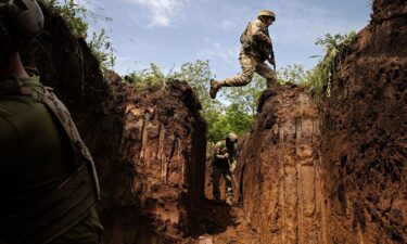 A Ukrainian Army soldier jumps over a gap in a defensive trench outside Kostyanynivka