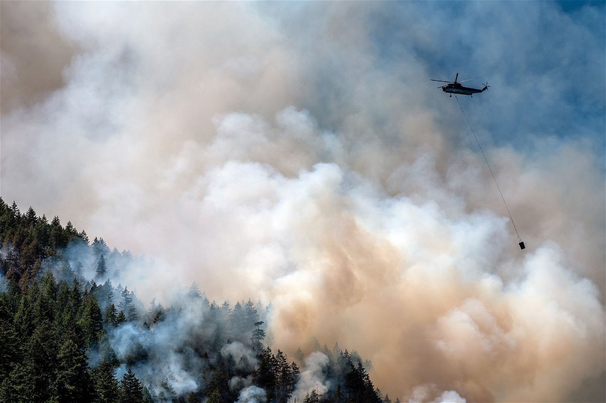<i>James MacDonald/Bloomberg/Getty Images</i><br/>A helicopter waterbomber flies above the Cameron Bluffs wildfire near Port Alberni