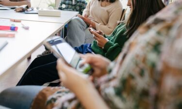 A group of high school students look at their smartphones while taking a short break during class.