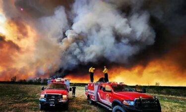 Firefighters stand on a Kamloops Fire Rescue truck at a wildfire near Fort St. John