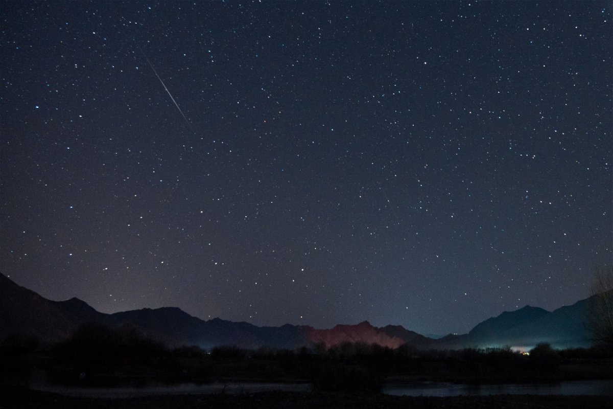 <i>Jiang Feibo/China News Service/VCG/Getty Images</i><br/>The Geminid meteor shower streaks across the night sky over the Lhasa River in Tibet in December 2022. The Geminid meteor shower