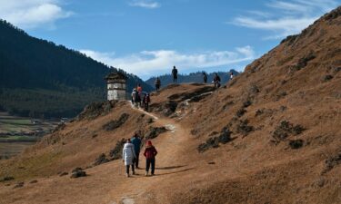 Tourists walk in the Phobjikha Valley in Wangdue Phodrang province in Bhutan. Bhutan will lower the nightly fees it charges tourists who stay more than four days in an attempt to boost visitor numbers.