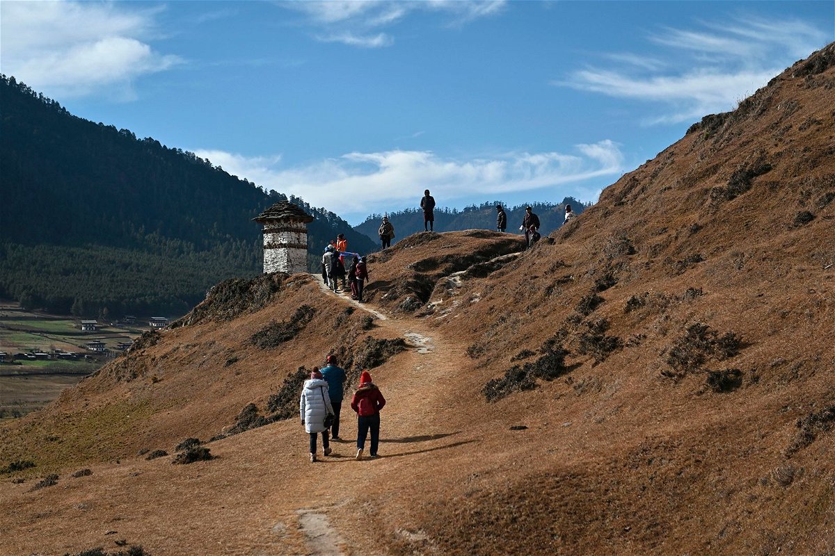 <i>Lillian Suwanrumpha/AFP/Getty Images</i><br/>Tourists walk in the Phobjikha Valley in Wangdue Phodrang province in Bhutan. Bhutan will lower the nightly fees it charges tourists who stay more than four days in an attempt to boost visitor numbers.