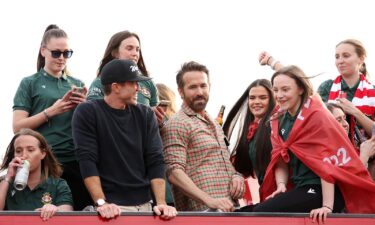 McElhenney and Reynolds celebrate with players of Wrexham's women's team during a bus parade celebration following its title-winning season.