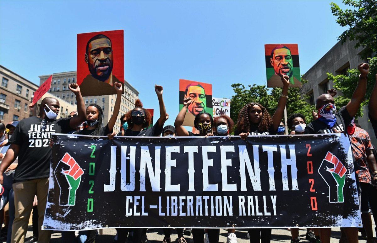 <i>AFP/Getty Images</i><br/>Demonstrators at a 2020 Juneteenth rally in New York hold up pictures of George Floyd.
