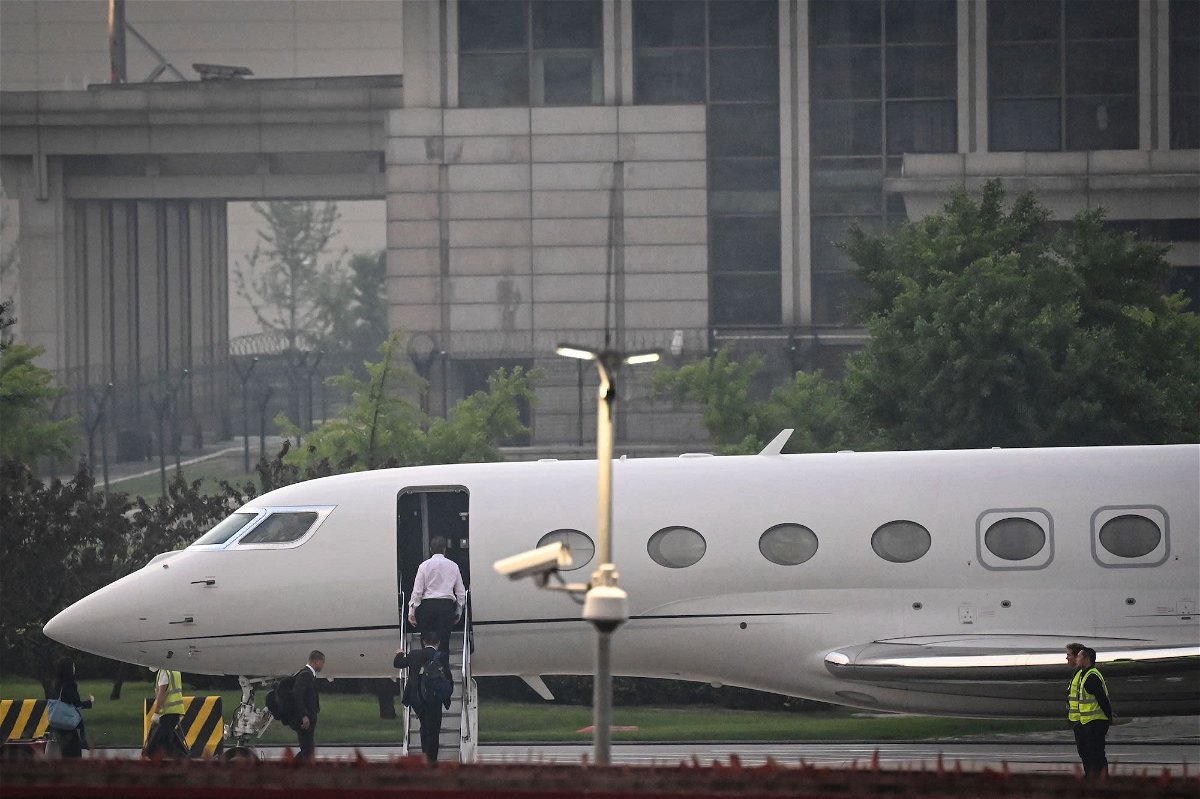 <i>Jade Gao/AFP/Getty Images</i><br/>Elon Musk (in white) boards his private jet before departing from Beijing Capital International Airport on May 31. He was traveling to Shanghai.