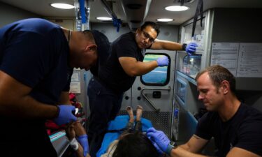 Firefighter EMTs treat a migrant woman suffering from heat exhaustion in the border community of Eagle Pass