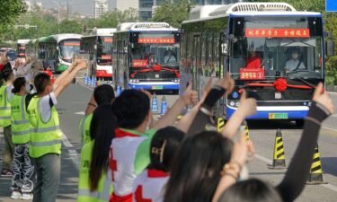 People make thumbs-up gestures to buses carrying students to the Gaokao entrance exam in Yantai