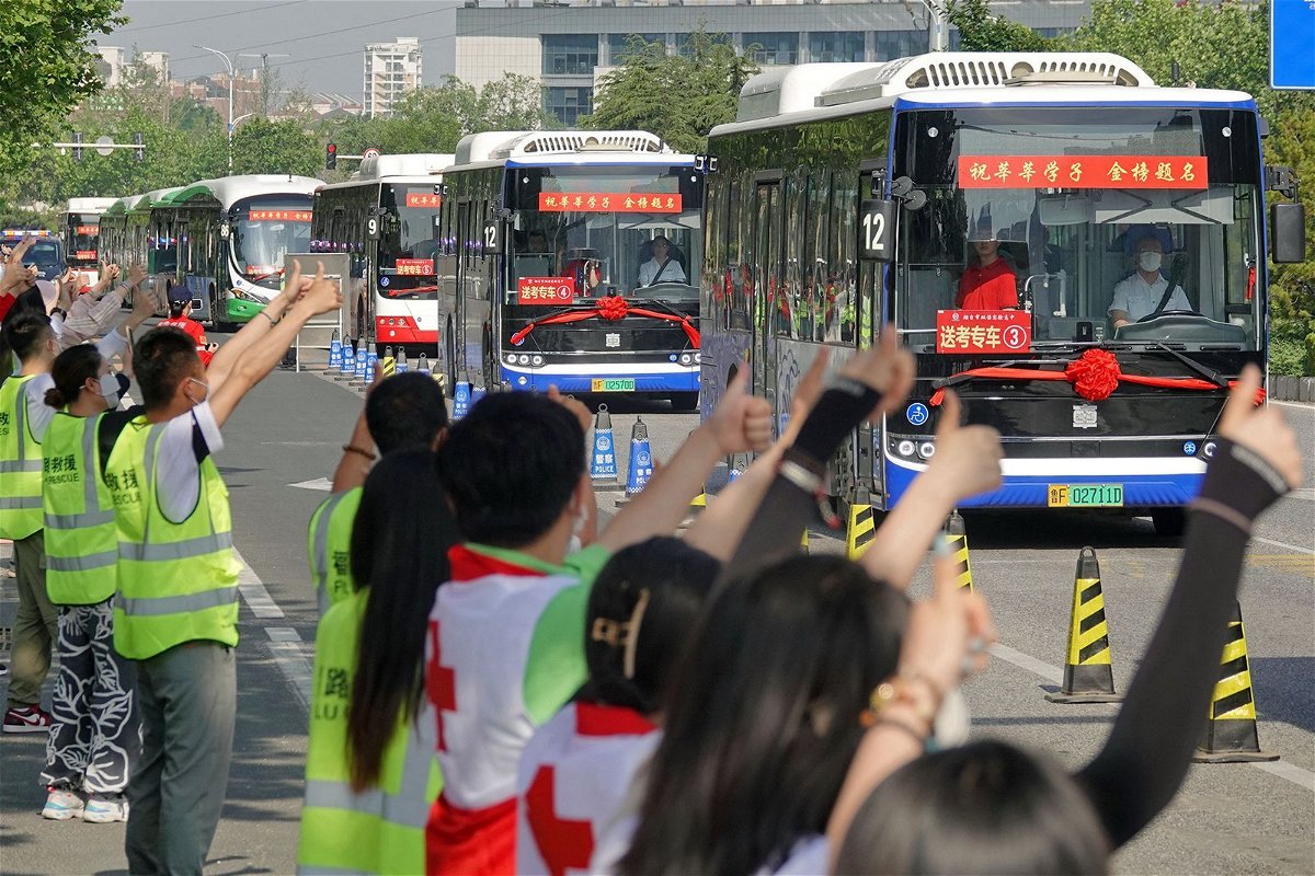 <i>Stringer/AFP/Getty Images</i><br/>People make thumbs-up gestures to buses carrying students to the Gaokao entrance exam in Yantai