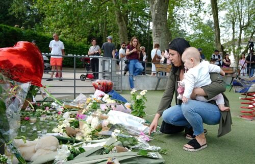 People lay flowers near the scene at a lakeside park in Annecy