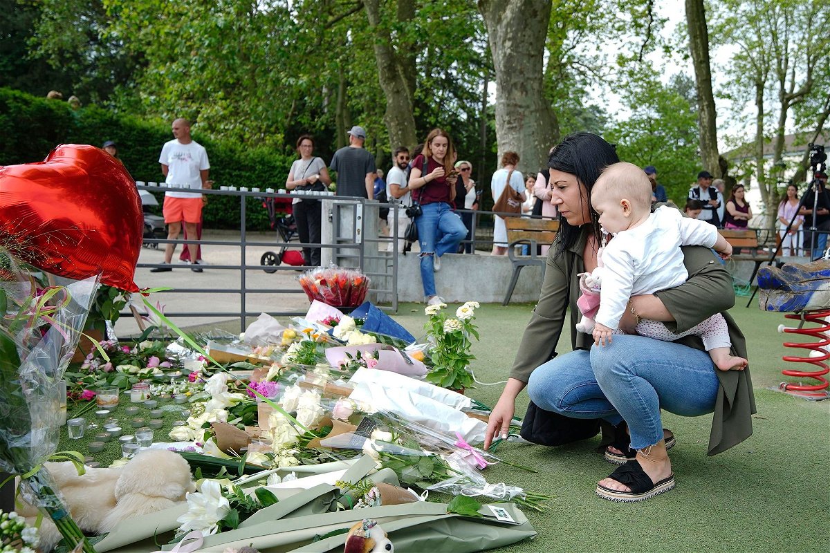 <i>Peter Byrne/Press Association/AP</i><br/>A woman holding a baby lays flowers near the scene at a lakeside park in Annecy