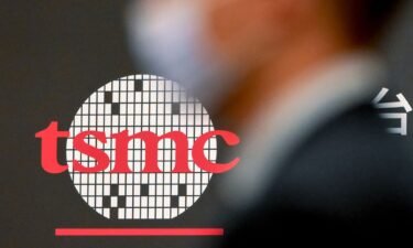 A man walks past a logo of Taiwan Semiconductor Manufacturing Company.