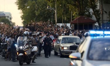 The royal motorcade carrying Thailand's Queen Suthida and Prince Dipangkorn drives past a group of anti-government demonstrators in Bangkok in October 2020.