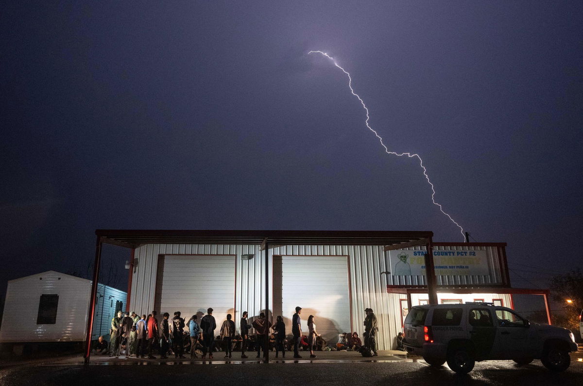 <i>Andrew Caballero-Reynolds/AFP/Getty Images</i><br/>US Border Patrol agents keep watch over migrants that just turned themselves in after crossing over from Mexico as they wait for a bus to take them to a processing center in Fronton