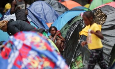 Migrants from Haiti look on outside their tent in the Giordano Bruno park