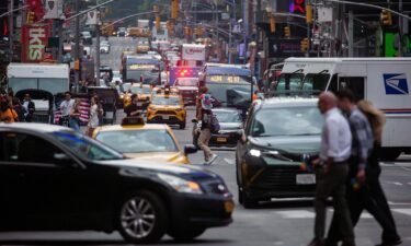 Pedestrians cross a street past traffic in the Midtown neighborhood of New York on June 17.