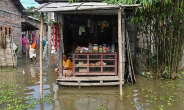 A woman sits at her partially submerged shop in the flood affected area of Rangia